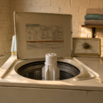 Top load washing machine with lid open showing central agitator post inside drum