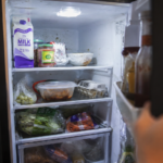 open refrigerator not cooling with groceries inside warm kitchen