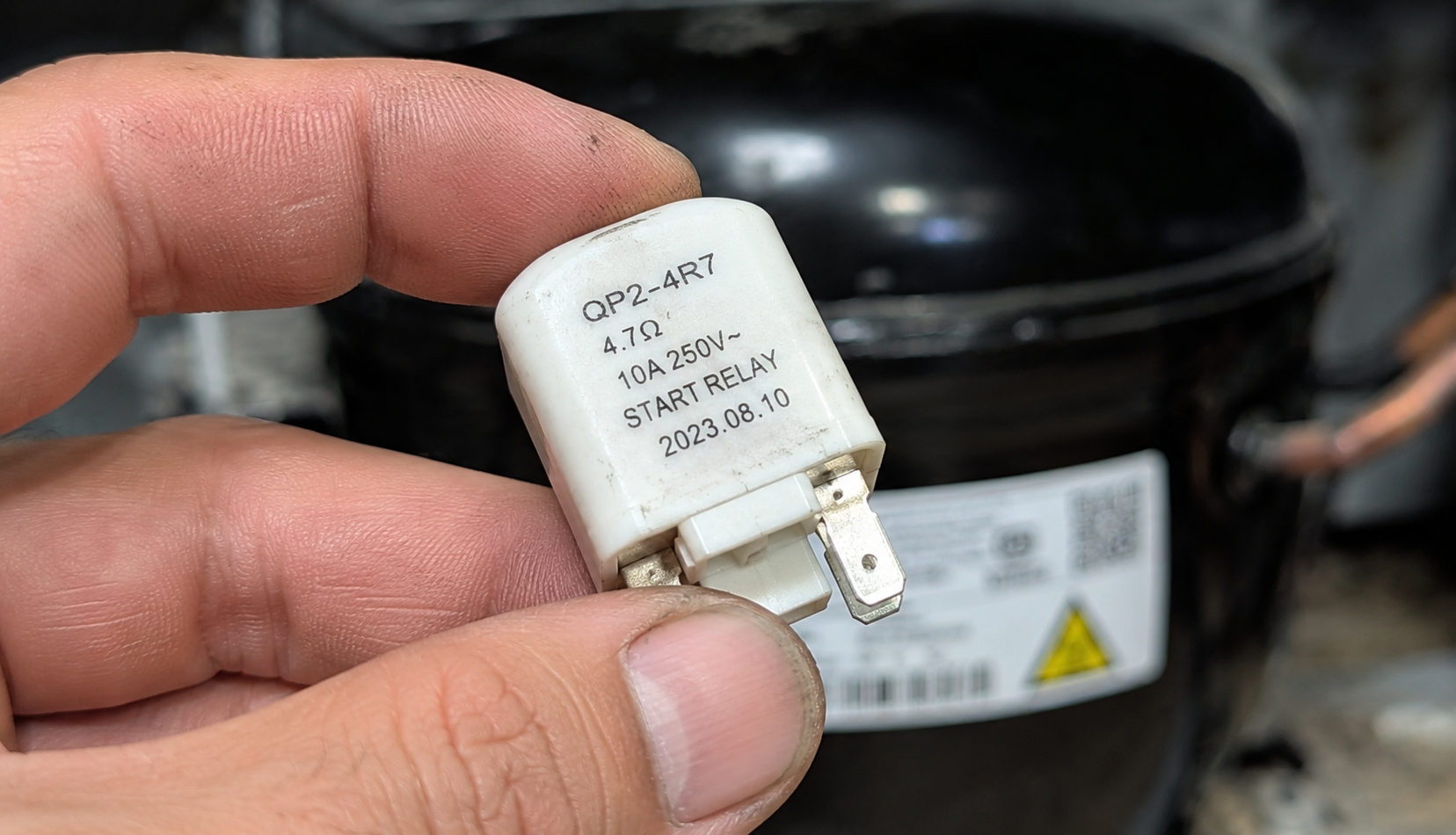 ChatGPT Image Jun 18, 2026, 08_50_18 PM hand holding refrigerator start relay removed from compressor