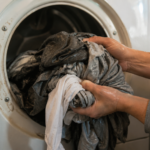 Hands pulling wet laundry from a dryer that stopped producing heat