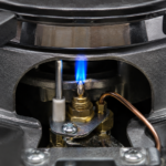 Gas stove pilot light burning blue flame inside burner assembly