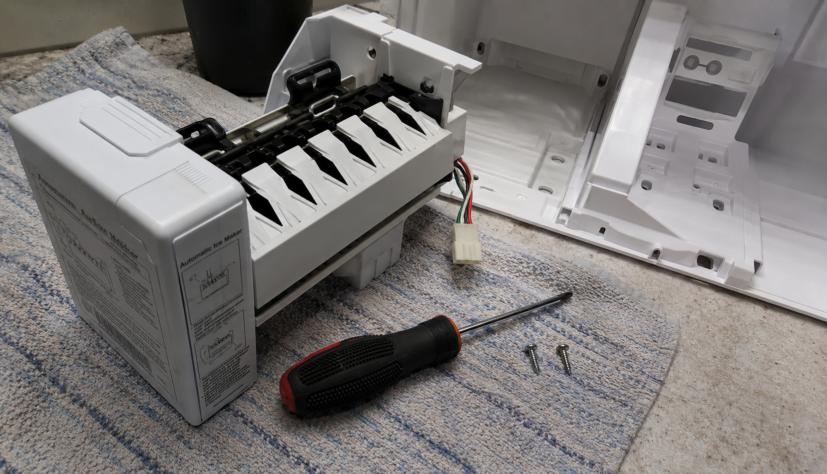 ChatGPT Image Aug 13, 2026, 11_23_25 PM Disconnected Samsung ice maker assembly with screwdriver and mounting screws