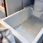 Mineral buildup and chalky scale inside an open ice maker bin