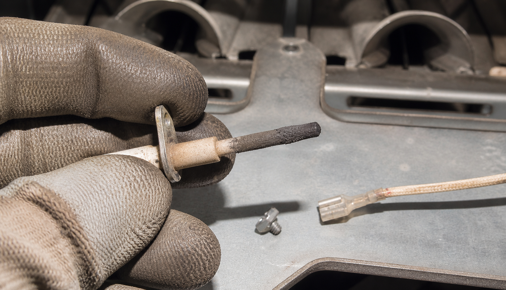 Close-up of dirty furnace flame sensor rod removed for cleaning